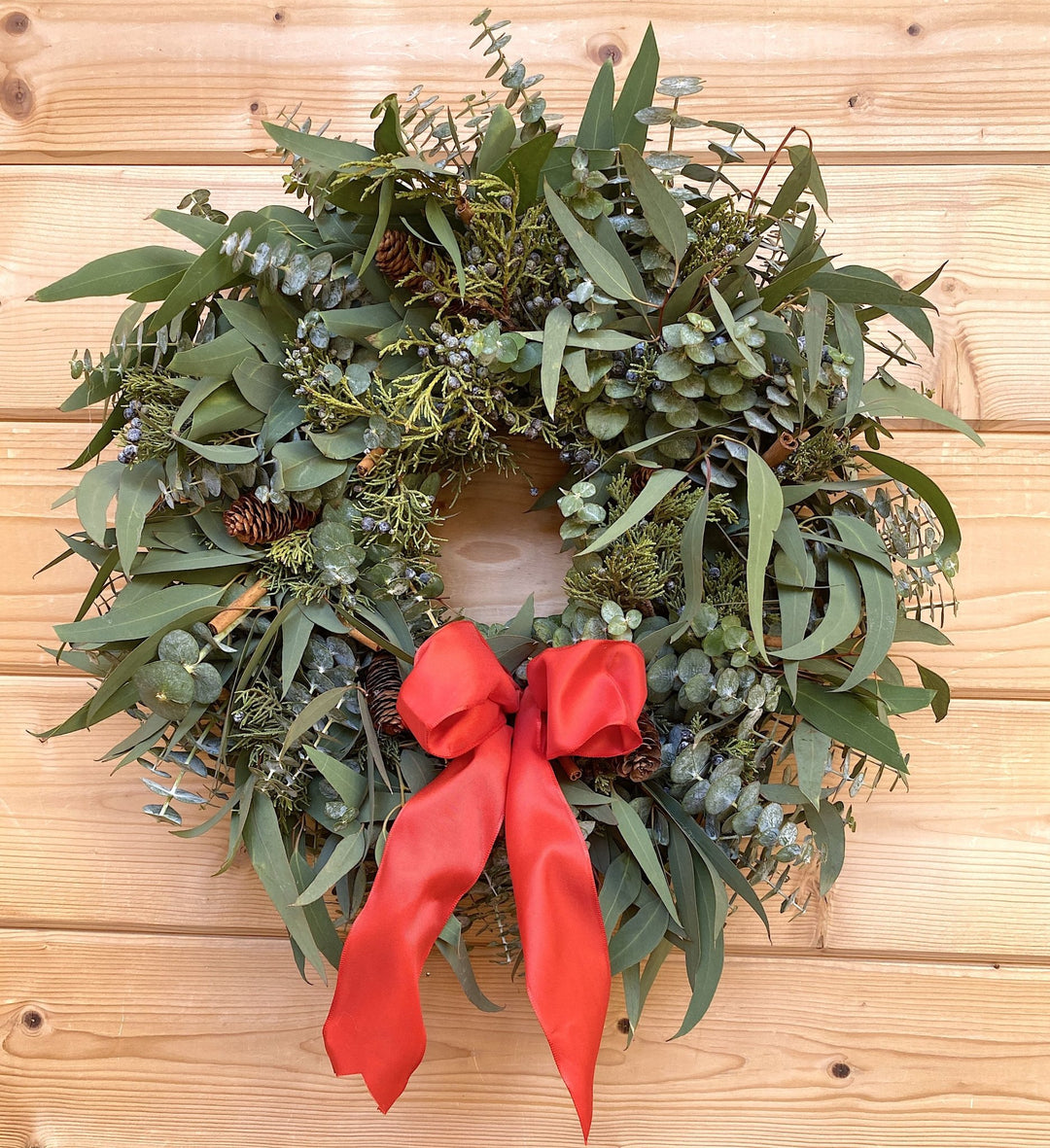 Cinnamon Pine Cone Wreath - Creekside Farms Fragrant eucalyptus, juniper with pine cones, cinnamon sticks & red bow wreath 18"